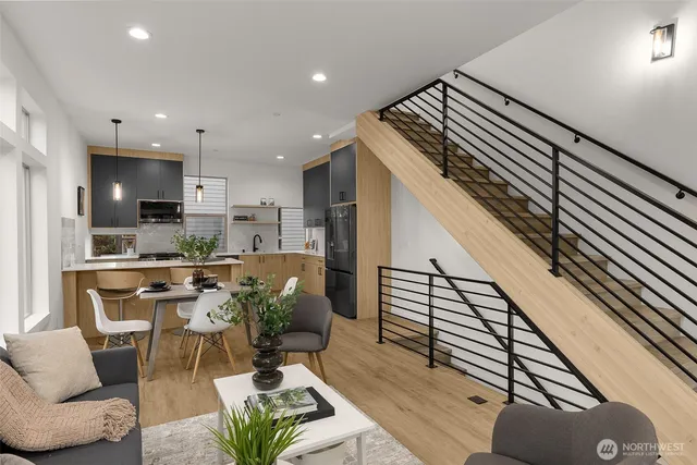 a living room with stainless steel appliances furniture a rug and a kitchen view