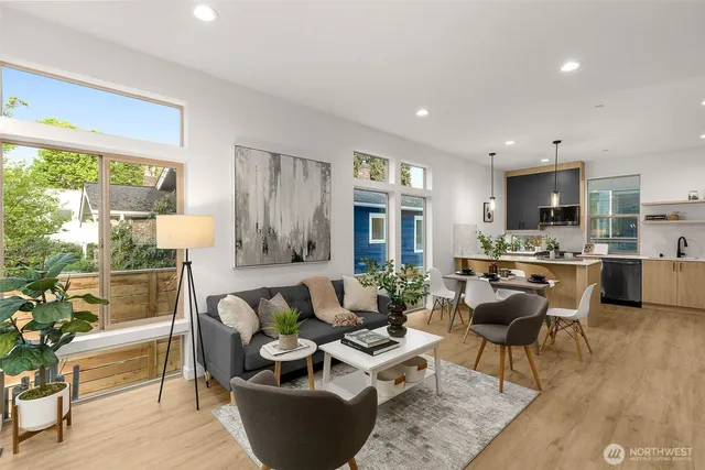 a living room with couches and kitchen view with wooden floor