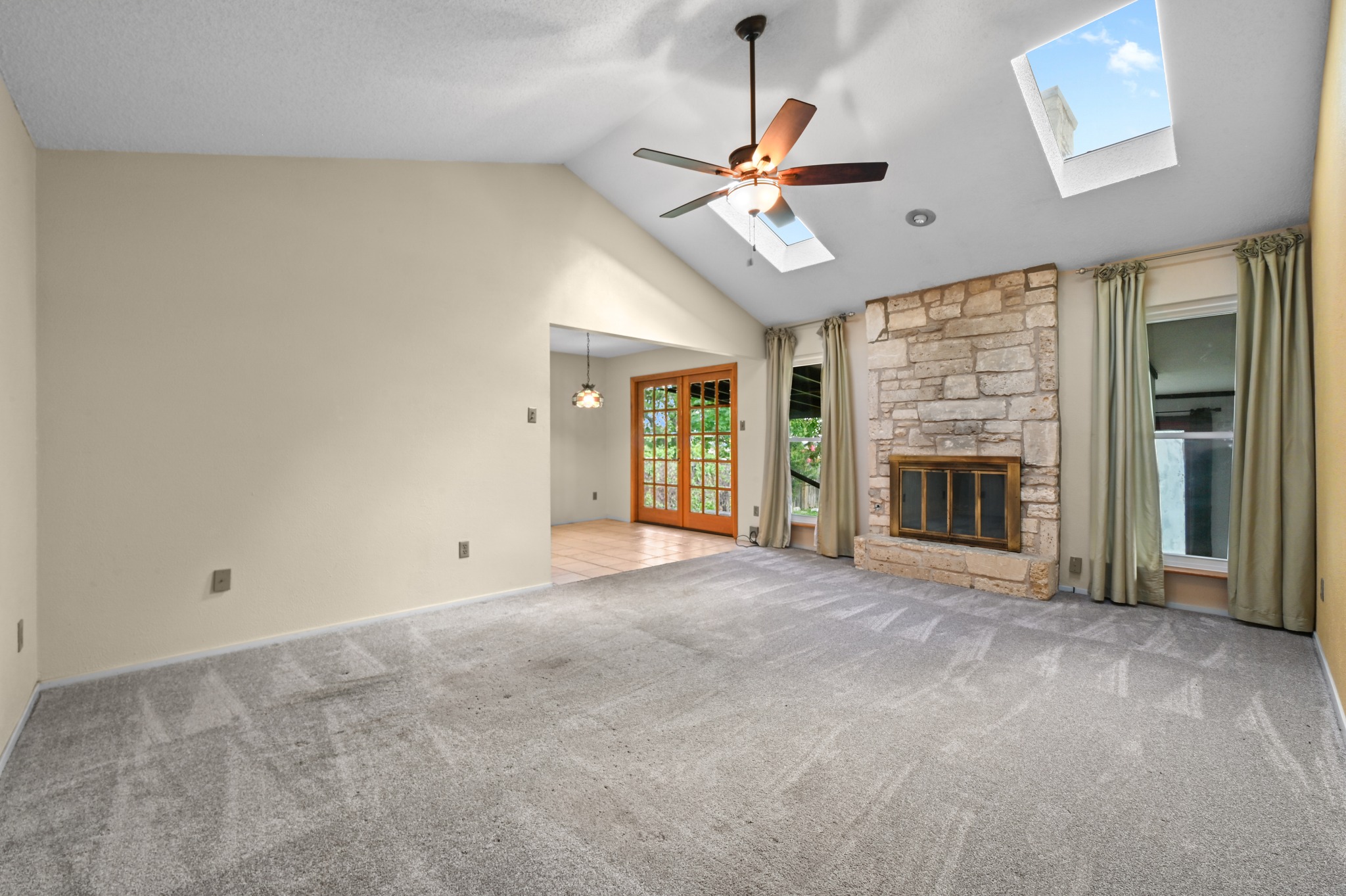 10504 Hard Rock Road Austin, TX 78750 - Photo 7 of 28 A spacious living room features vaulted ceilings, skylights, and a stone fireplace.