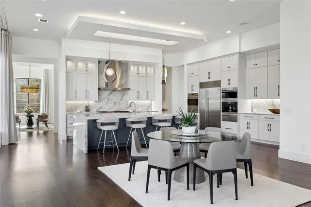 a dining room with stainless steel appliances kitchen island granite countertop a dining table chairs and a refrigerator