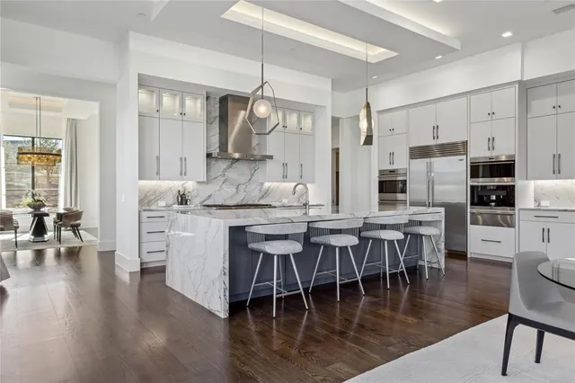 a dining room with stainless steel appliances kitchen island granite countertop a table chairs and a view of living room