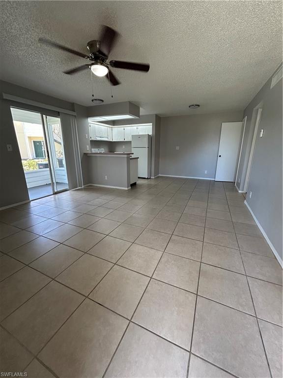 1989 Rookery Bay Drive, Unit 704 Naples, FL 34114 - Photo 2 of 10 Unfurnished living room with a textured ceiling, light tile patterned floors, and a ceiling fan