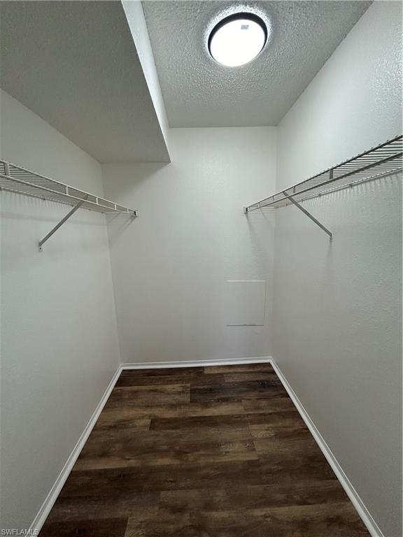 1989 Rookery Bay Drive, Unit 704 Naples, FL 34114 - Photo 7 of 10 Walk in closet with dark wood-style flooring
