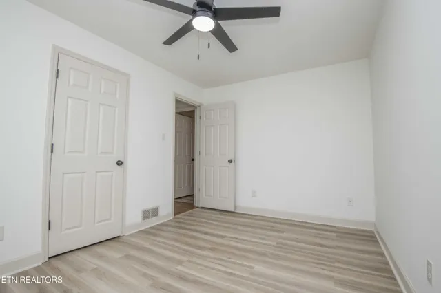a view of a room with wooden floor and ceiling fan