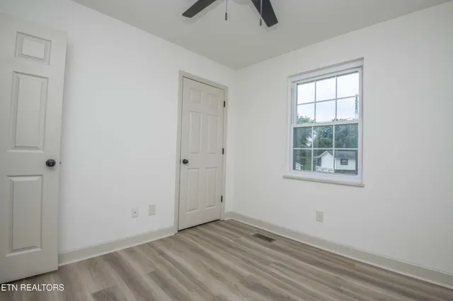 an empty room with a window and a ceiling fan
