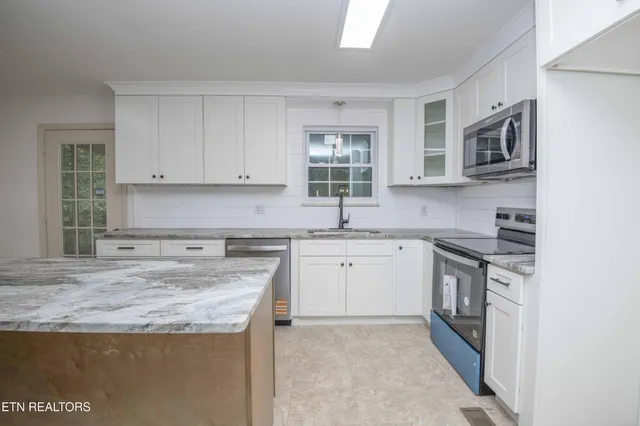 a kitchen with stainless steel appliances granite countertop a sink stove and cabinets