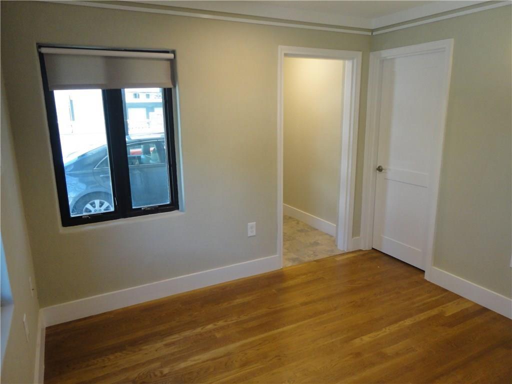 3311 Speedway, Unit D Austin, TX 78705 - Photo 14 of 23 Room featuring hardwood floors, a window with a roller shade, and light-colored walls with white trim