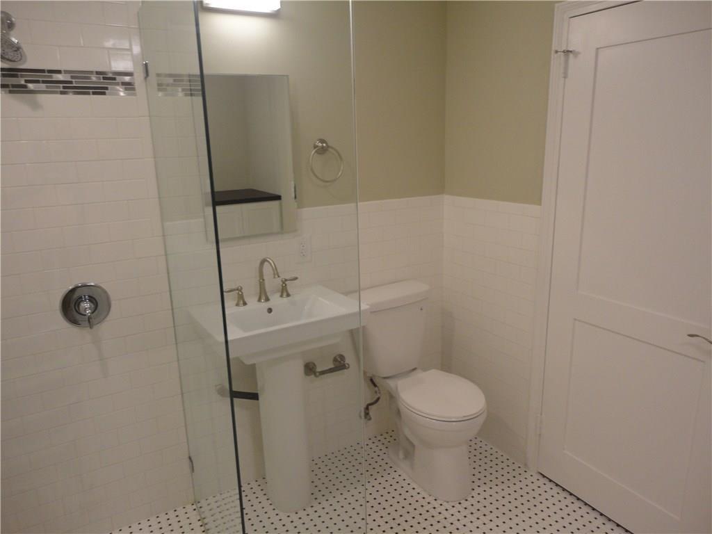 3311 Speedway, Unit D Austin, TX 78705 - Photo 18 of 23 Bathroom featuring a shower with glass enclosure, a pedestal sink with a mirror, a toilet, and white tile flooring