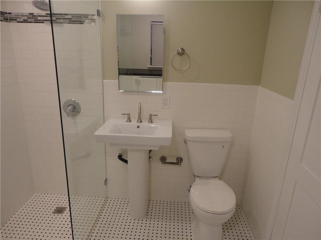 3311 Speedway, Unit D Austin, TX 78705 - Photo 19 of 23 This bathroom features white subway tile walls, a pedestal sink, a toilet, and a glass-enclosed shower with a tiled floor