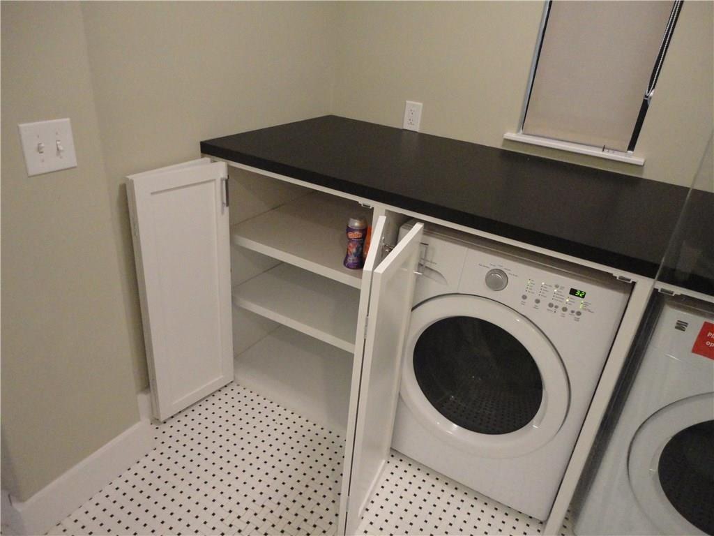 3311 Speedway, Unit D Austin, TX 78705 - Photo 22 of 23 The utility area features a white washer, white cabinetry with shelving, a dark countertop, and tiled flooring
