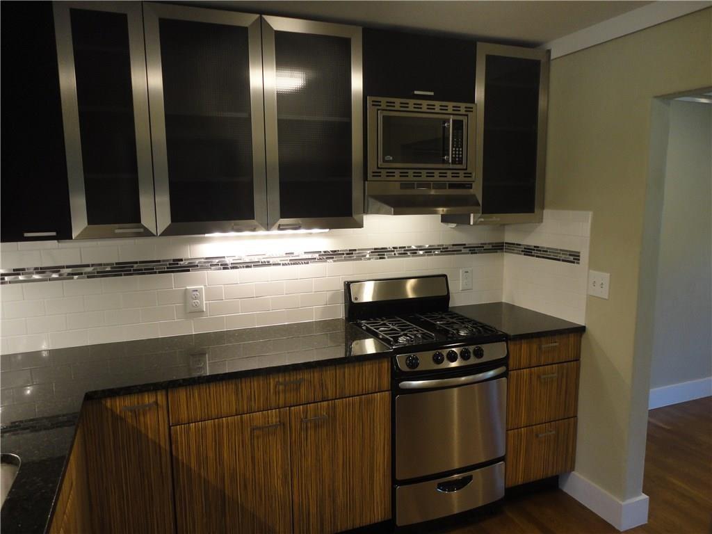 3311 Speedway, Unit D Austin, TX 78705 - Photo 6 of 23 The kitchen features stainless steel appliances, dark countertops, and a white subway tile backsplash with a decorative accent band