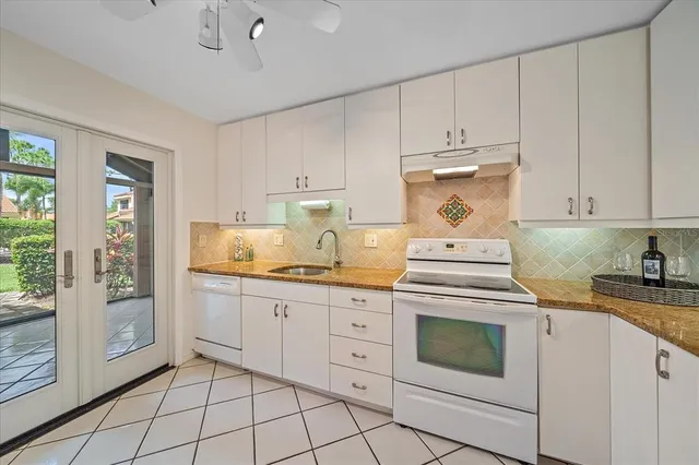 a kitchen with granite countertop white cabinets and white appliances