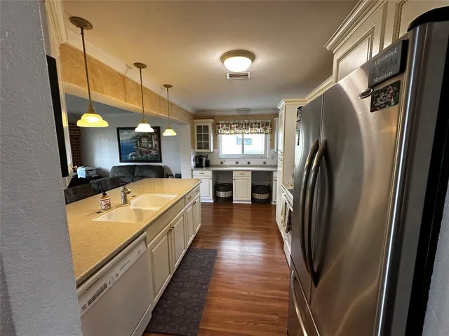 a large kitchen with stainless steel appliances a refrigerator a stove a sink dishwasher a oven with wooden floor