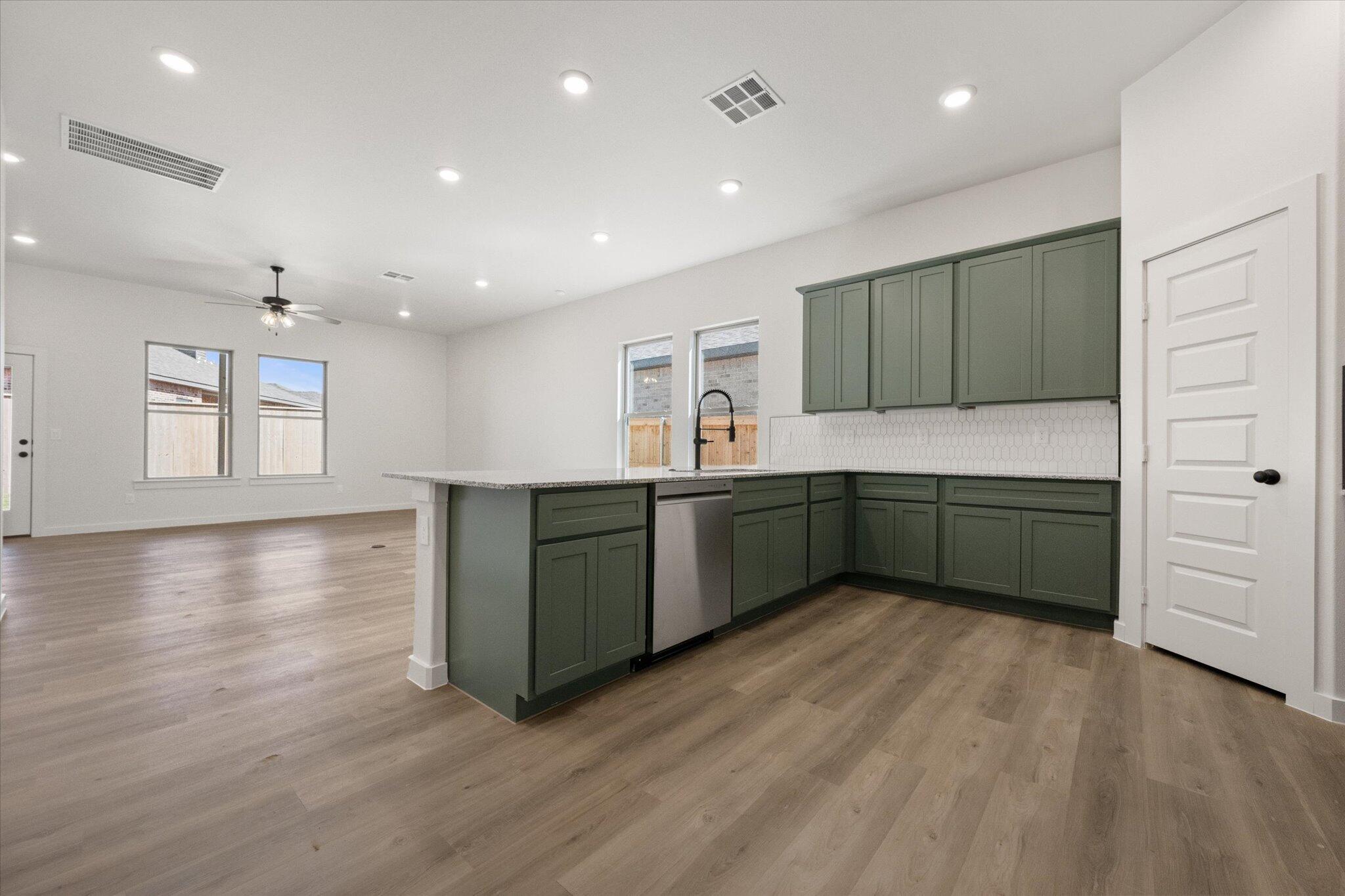 7003 53rd Street Lubbock, TX 79407 - Photo 12 of 25 a kitchen with stainless steel appliances a sink dishwasher a refrigerator and a oven with wooden floor