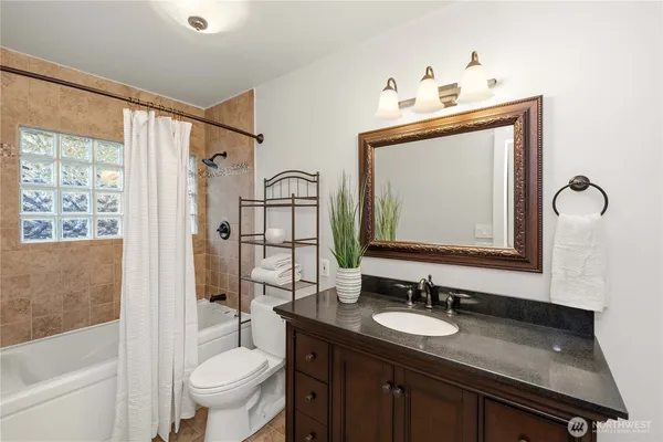 a bathroom with a granite countertop sink a mirror and a shower