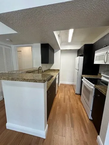 a kitchen with granite countertop a sink stove and refrigerator