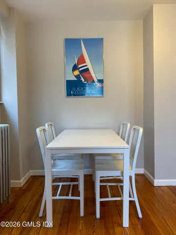 a view of a dining room with furniture wooden floor and painting on the wall