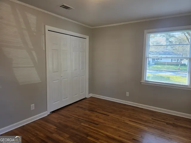 a view of an empty room with wooden floor and a window