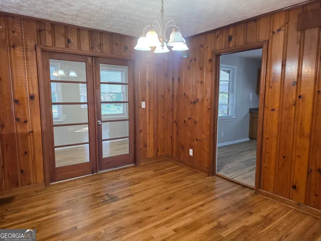 an empty room with wooden floor closet and windows