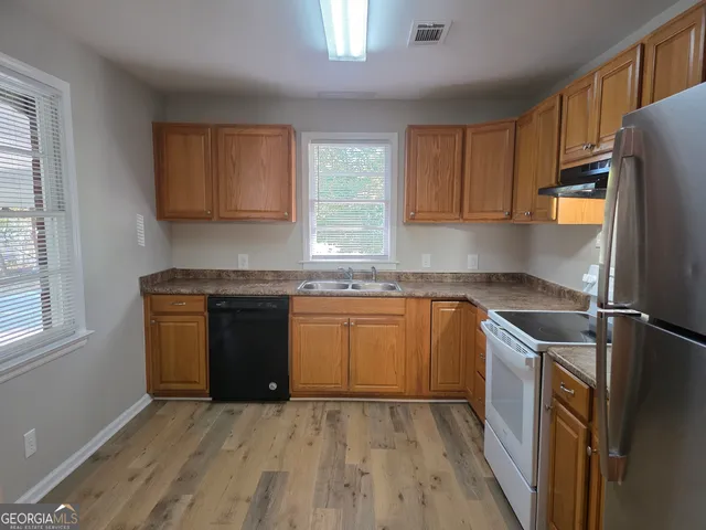 a kitchen with granite countertop a refrigerator stove top oven and sink