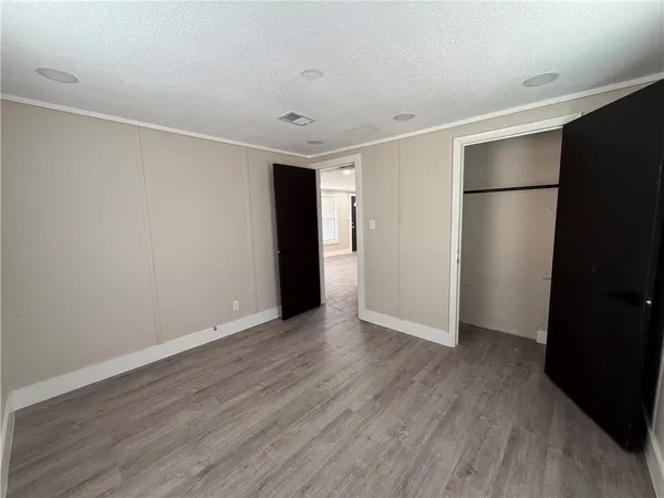 a view of an empty room with wooden floor and closet