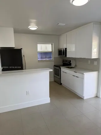 a kitchen with stainless steel appliances a stove a microwave a sink a refrigerator and white cabinets
