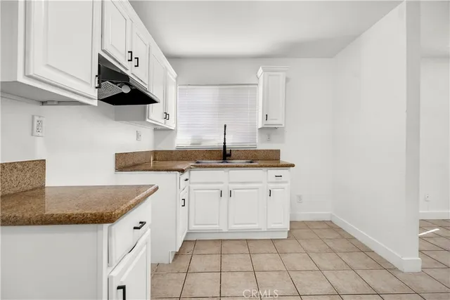 a kitchen with granite countertop white cabinets and a sink