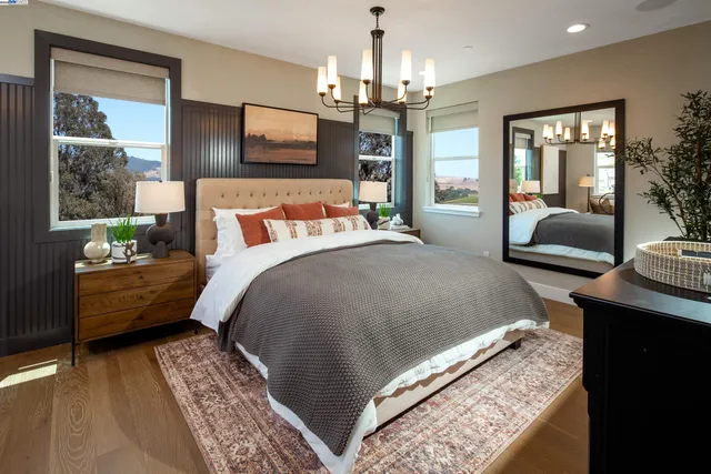 a spacious bedroom with a bed a chandelier and a dresser