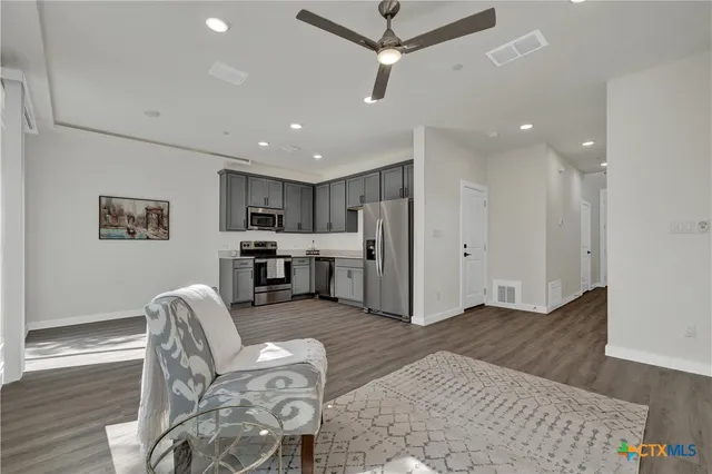 a view of a hallway with wooden floor and a ceiling fan