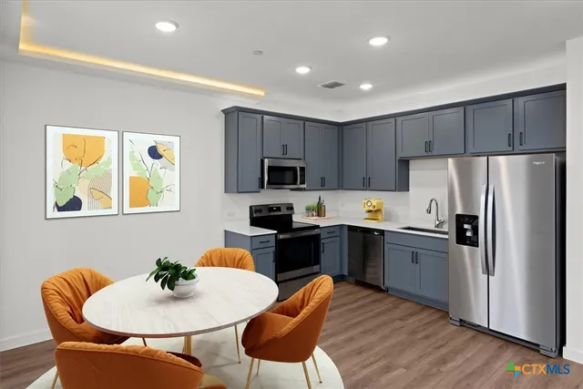 a kitchen with granite countertop stainless steel appliances refrigerator sink and microwave