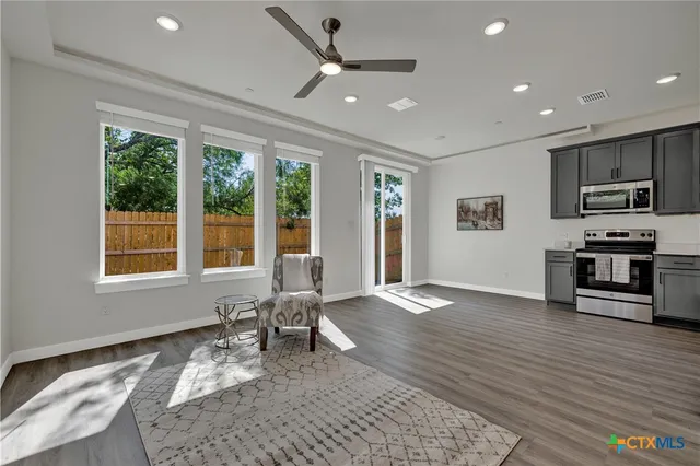 a living room with stainless steel appliances kitchen island granite countertop furniture and a refrigerator