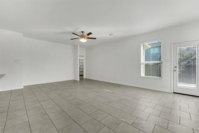 a view of a livingroom with kitchen appliances and a ceiling fan