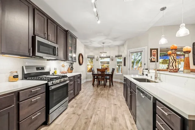 a kitchen with stainless steel appliances granite countertop sink stove top oven and cabinets