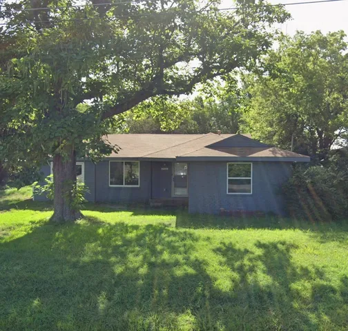 a brick house with a big yard and large trees