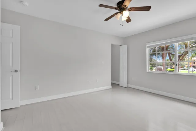an empty room with windows and fan
