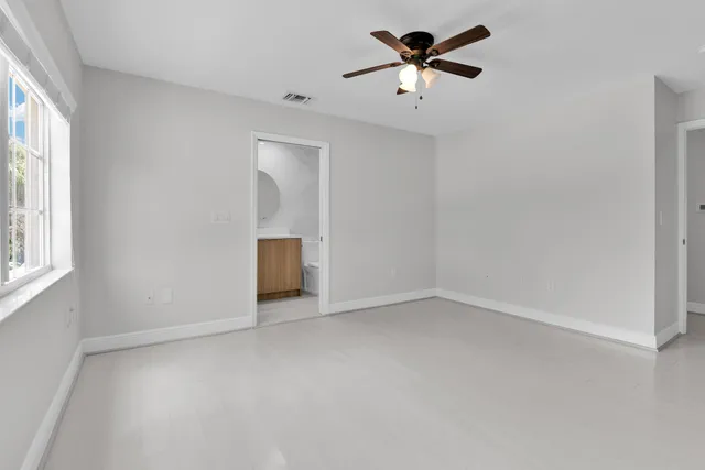 an empty room with windows and fan