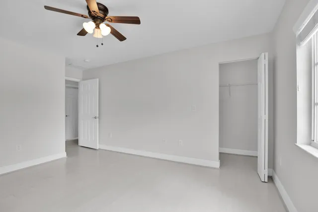 an empty room with a window and a fan