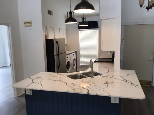 a kitchen with stainless steel appliances kitchen island a table chairs and refrigerator