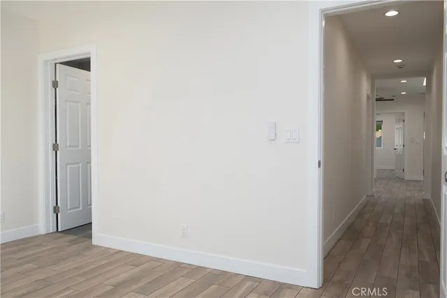 an empty room with wooden floor mirror and windows