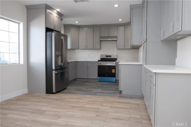 a kitchen with stainless steel appliances granite countertop a refrigerator a stove and a sink