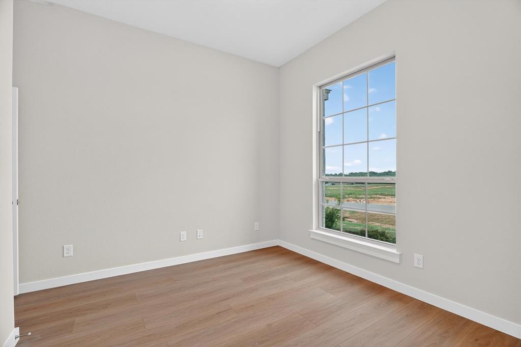 321 Skeen Peak Springtown, TX 76082 - Photo 24 of 37 Bright room with a large grid-pattern window, light neutral wall paint, white baseboards, and wood-finish flooring