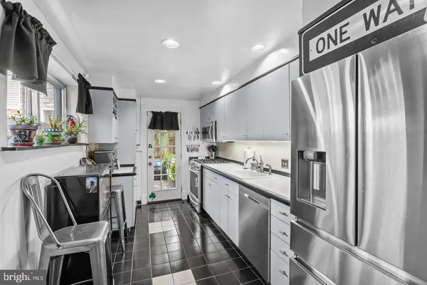 a kitchen with stainless steel appliances granite countertop a refrigerator a stove top oven a sink dishwasher and chairs