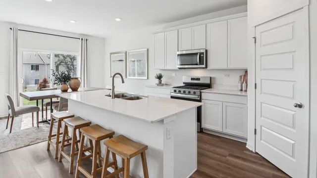 a kitchen with stainless steel appliances granite countertop a stove top oven a sink a dining table and chairs with wooden floor