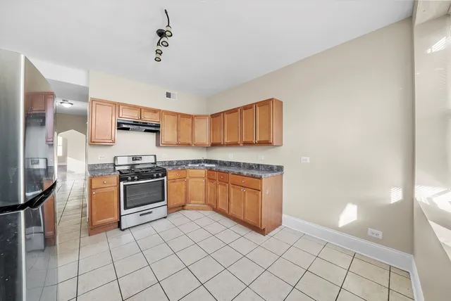 a large kitchen with granite countertop a stove a sink dishwasher and a refrigerator