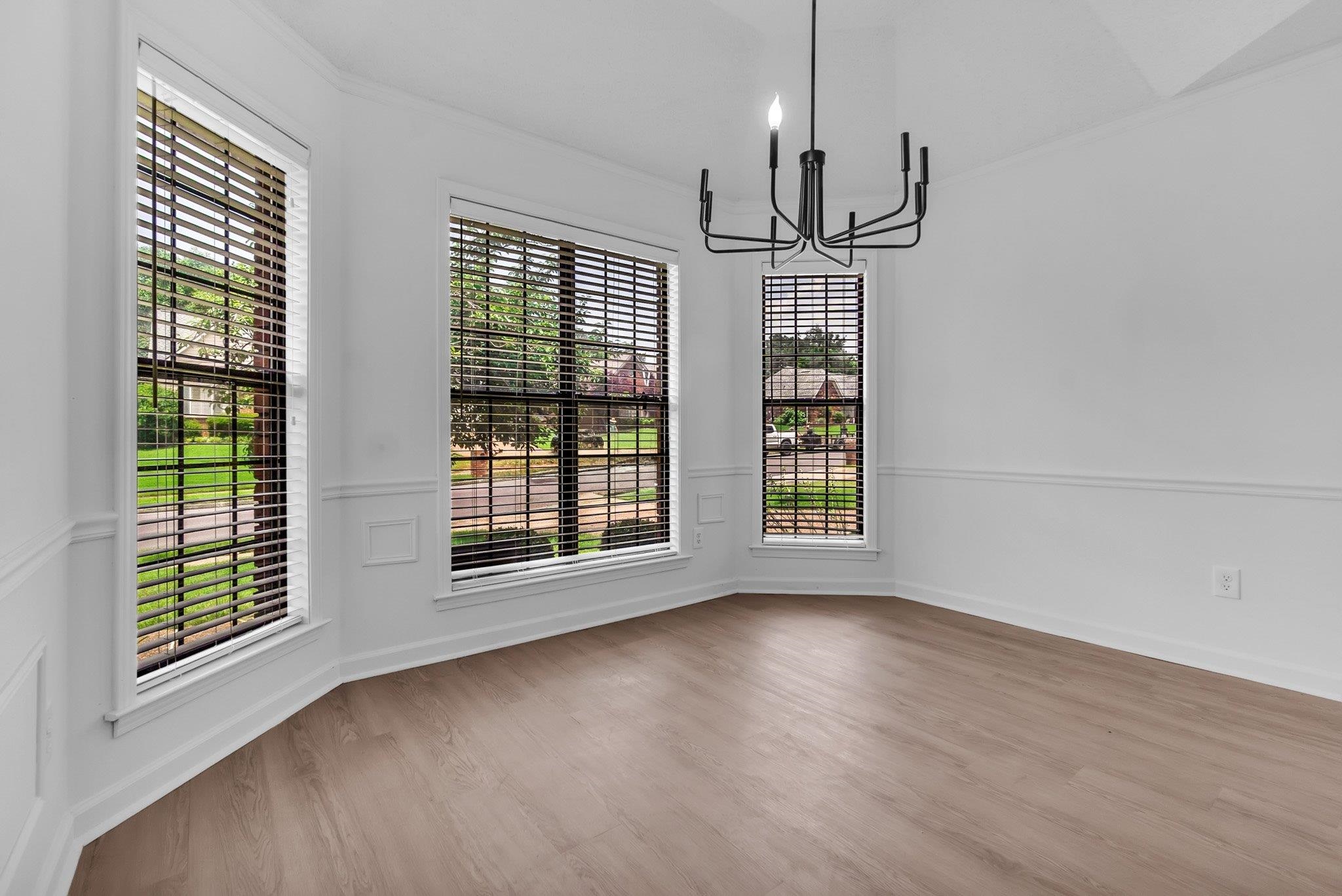 6613 Stephan Ridge Drive Bartlett, TN 38135 - Photo 7 of 24 Bay window with three large windows, crown molding, chair rail, wood-finish flooring, and a modern black chandelier