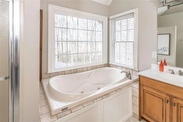 a spacious bathroom with double vanity sink a two mirror a window and a bathtub