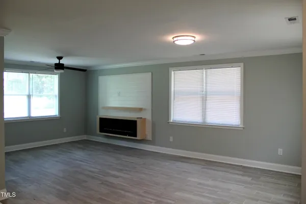 an empty room with windows and fireplace