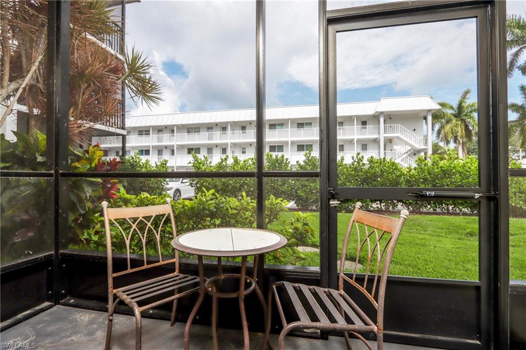 766 Central Avenue, Unit 119 Naples, FL 34102 - Photo 2 of 15 a view of a chairs and table in patio with a yard