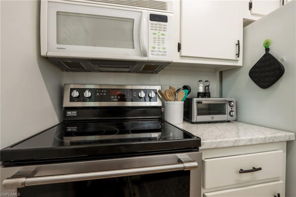 766 Central Avenue, Unit 119 Naples, FL 34102 - Photo 8 of 15 a stove top oven sitting inside of a kitchen and granite counter tops