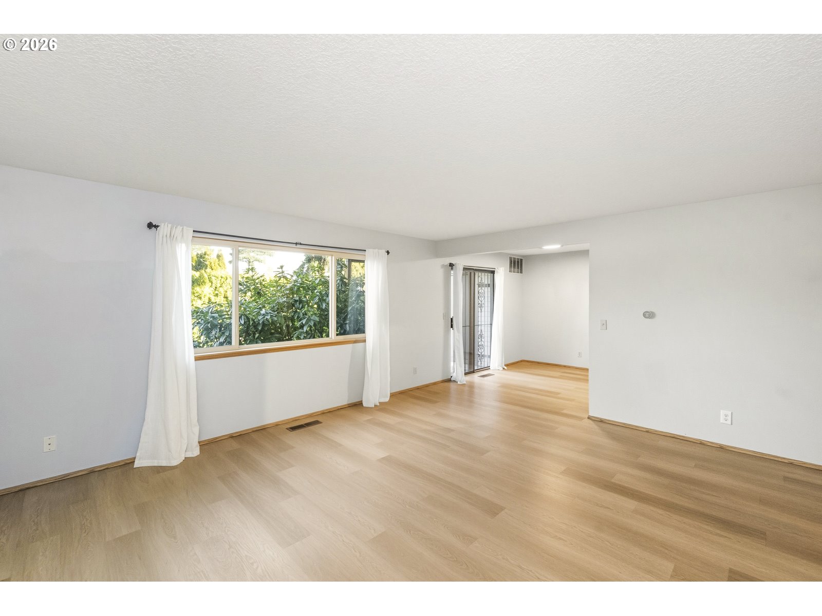 12516 Southeast Stark Street, Unit C Portland, OR 97233 - Photo 15 of 47 a view of an empty room with wooden floor and a window